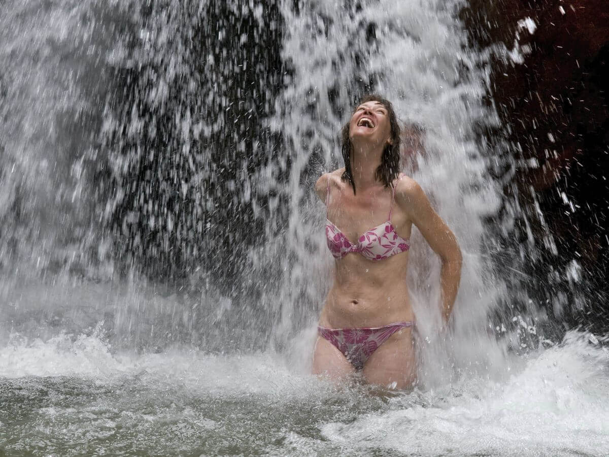 Frau steht unter Wasserfall
