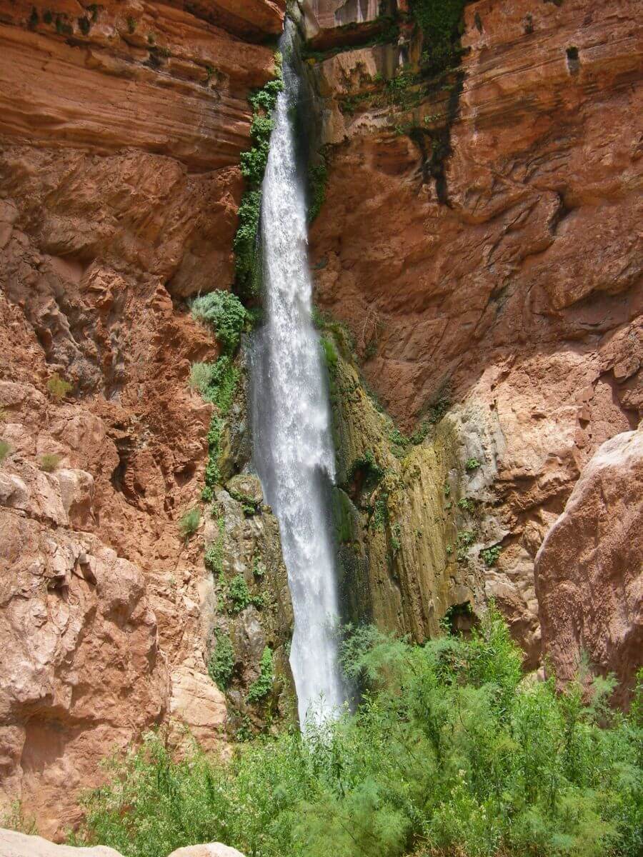 Schmaler Wasserfall aus rotbrauner Felswand