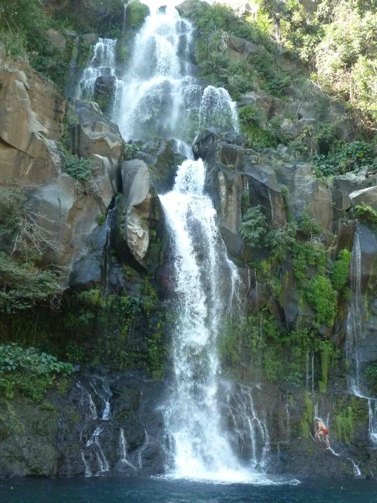 Wasserfall stürzt an einer Felswand runter.
