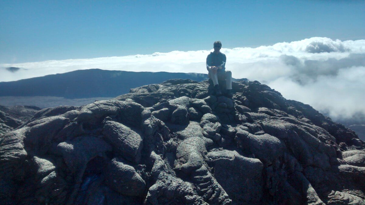 Marcus sitzt auf dem Lavagestein des Vulkans auf La Reunion.