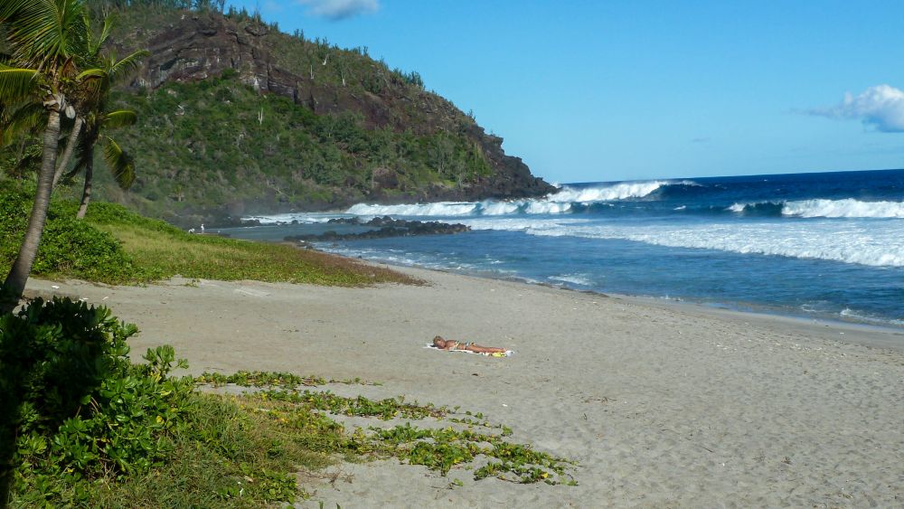 Heller Sandstrand mit blauem Meer und Brandung.