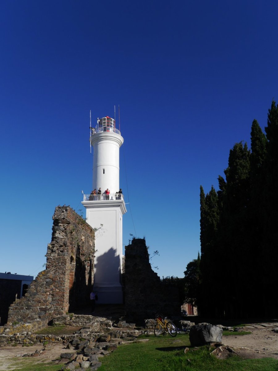 Weißer Leuchtturm vor blauem Himmel.