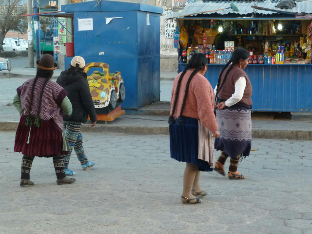 Indigene Frauen mit langen Zöpfen gehen auf der Straße.