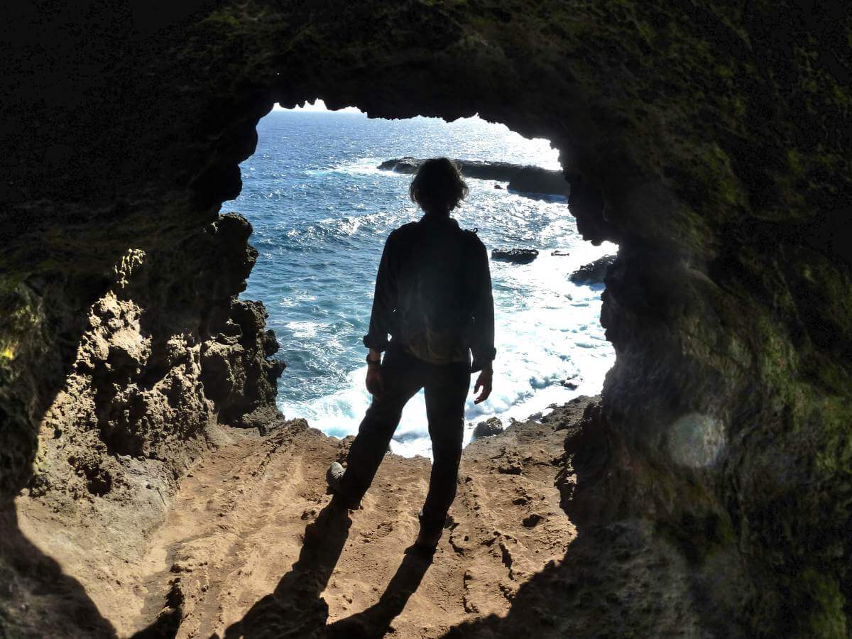 Marcus steht in der Öffnung der Höhle zum Meer.