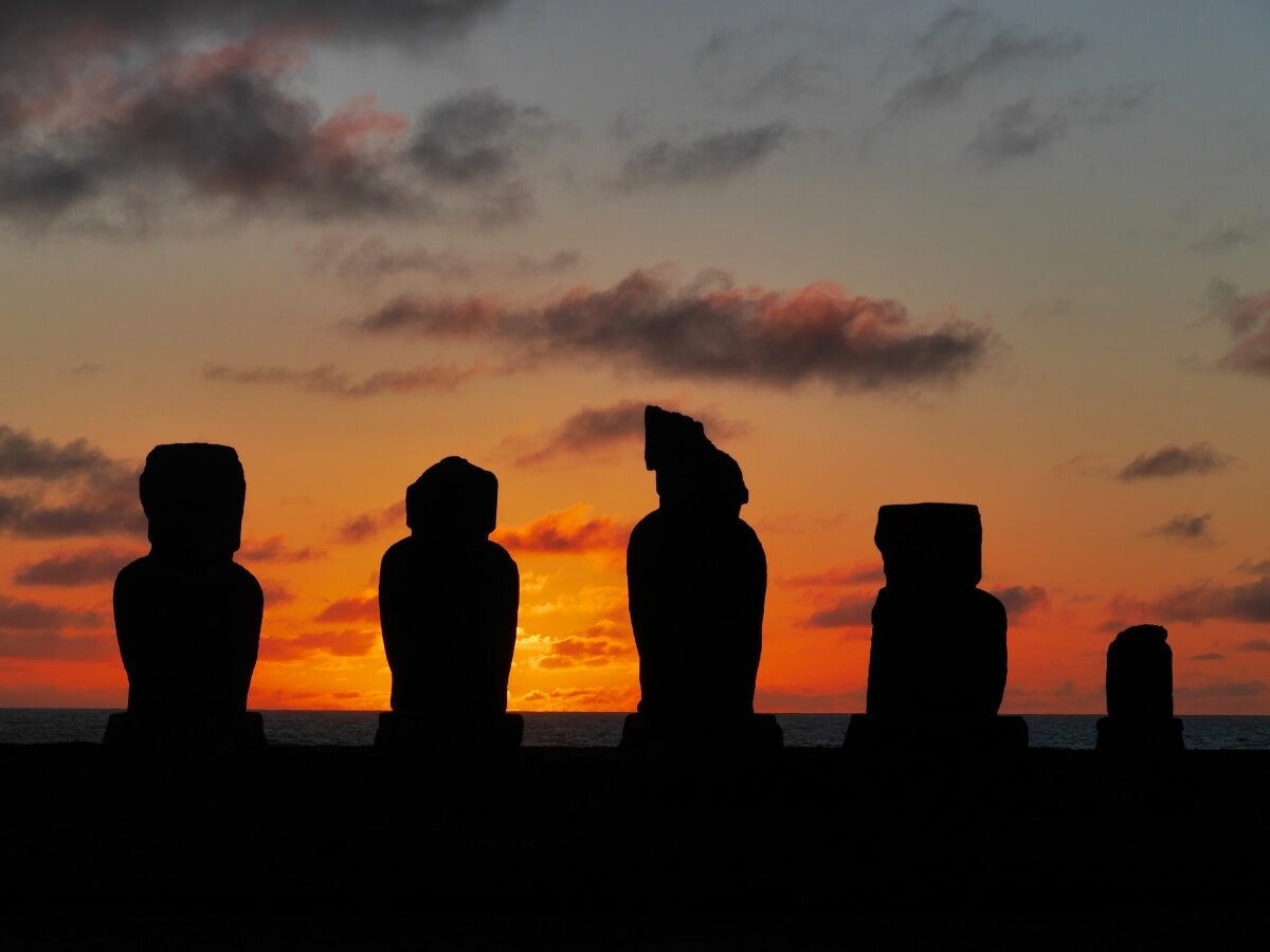 Fünf Figuren von Moai im Licht des Sonnenuntergangs.