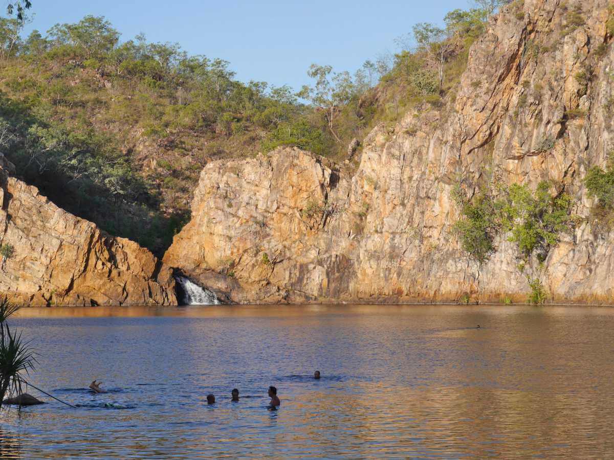 Schwimmer im See vor Felskulisse und Wasserfall.