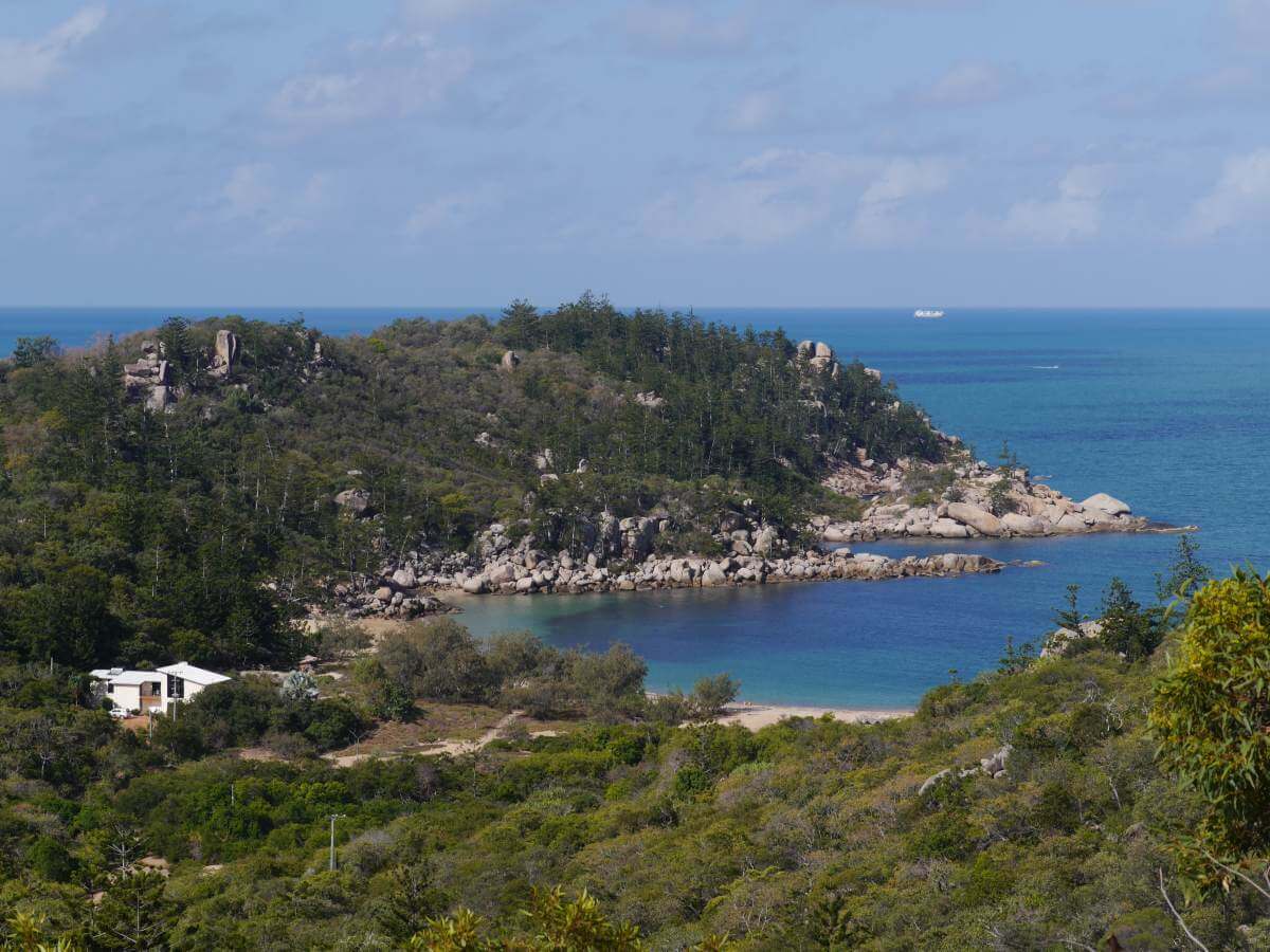 Blick auf grüne Hügel und eine Bucht am Meer.