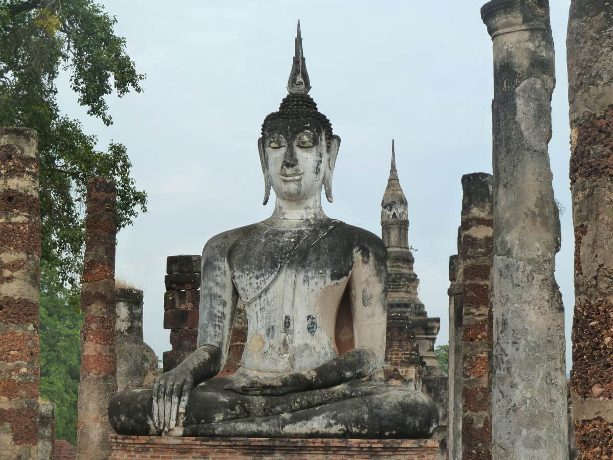 Große sitzende Buddha-Statue, umgeben von Säulen.