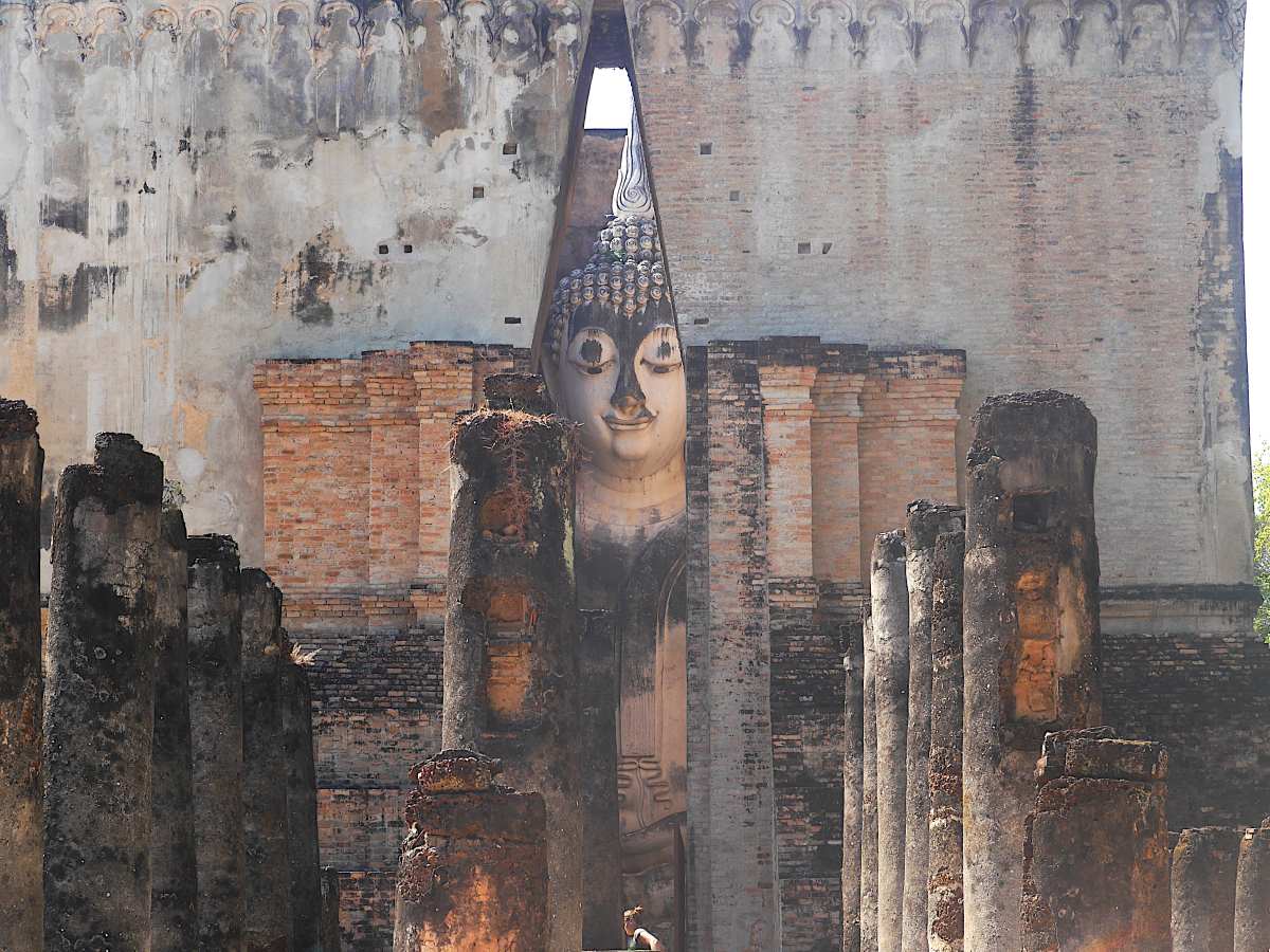 Tempel mit riesiger Buddhastatue, die durch Gebäudespalt zu sehen ist.