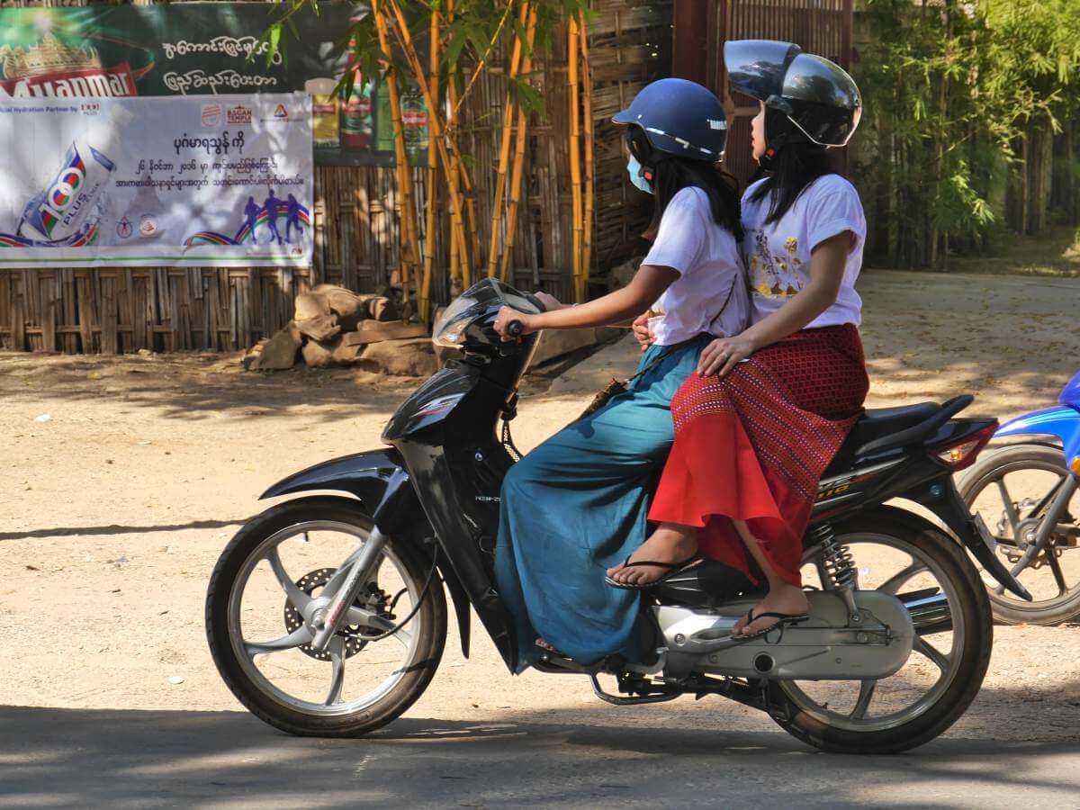 Zwei junge Frauen auf dem Motorroller, die hintere im Damensitz.