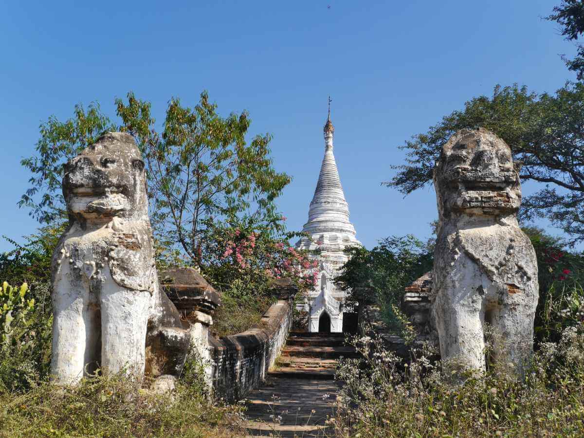 Weißer Stupa mit flankierenden Steinlöwen.