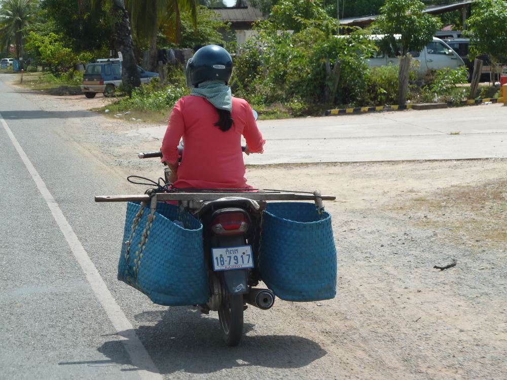 Frau auf Motorroller mit großem Gepäck.