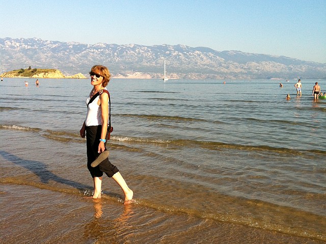 Gina watet am Strand von Rab durchs Wasser.