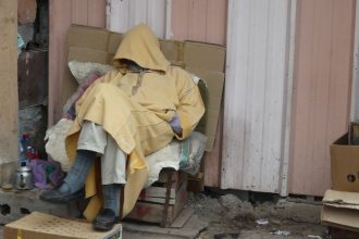 Mann schläft mit übers Gesicht gezogener Kapuze