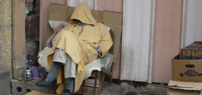 Mann schläft mit übers Gesicht gezogener Kapuze