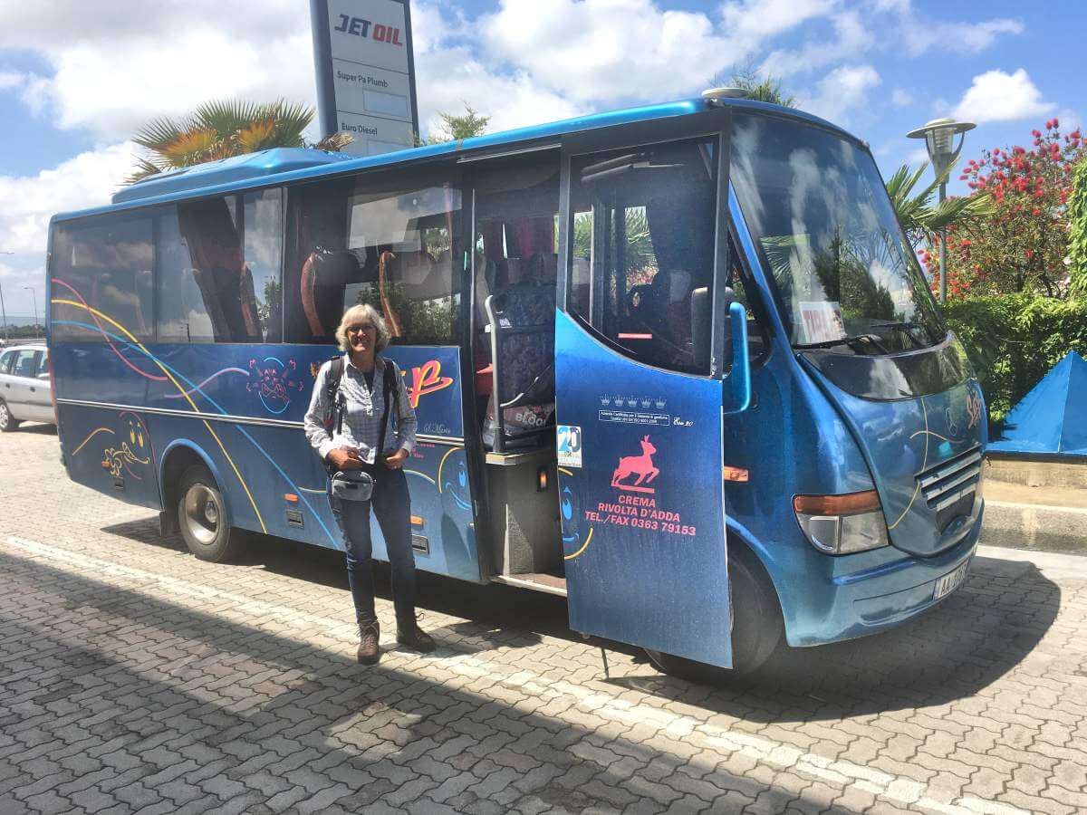 Gina steht vor einem blauen Bus.