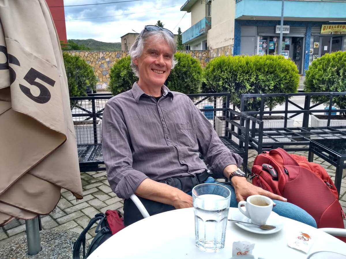 Marcus sitzt am Tisch mit einem Kaffee vor sich.