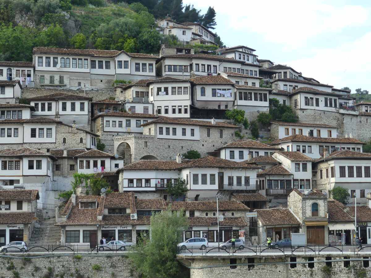 Viele Häuser in Berat mit Fensterreihen ziehen sich einen Hang entlang.