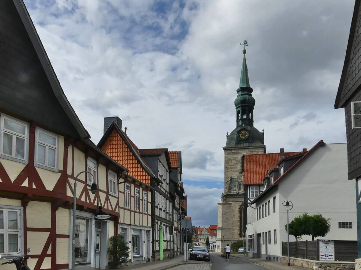 Blick durch Straße mit Fachwerkhäuseren auf die Kirche.