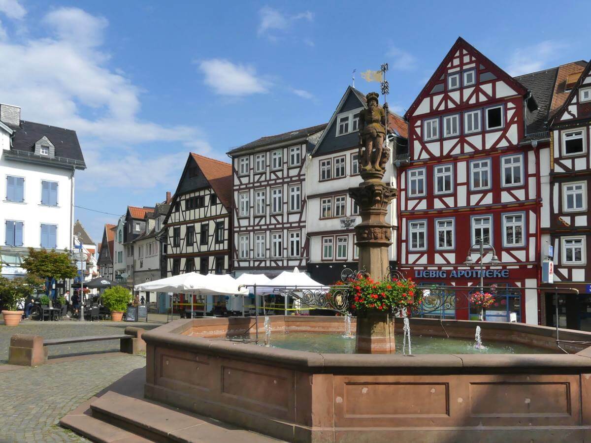 Brunnen auf Platz, von Fachwerk umgeben.