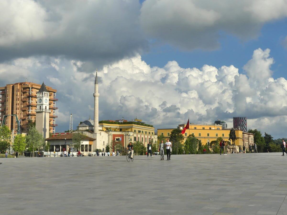 Großer Platz in Tirana mit Uhrturm und Minarett.