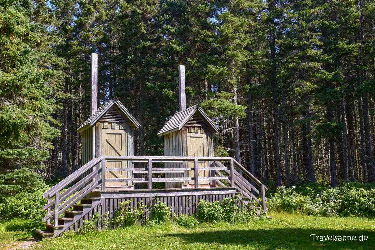 2 hölzerne Toiletten-Häuschen am Waldrand,