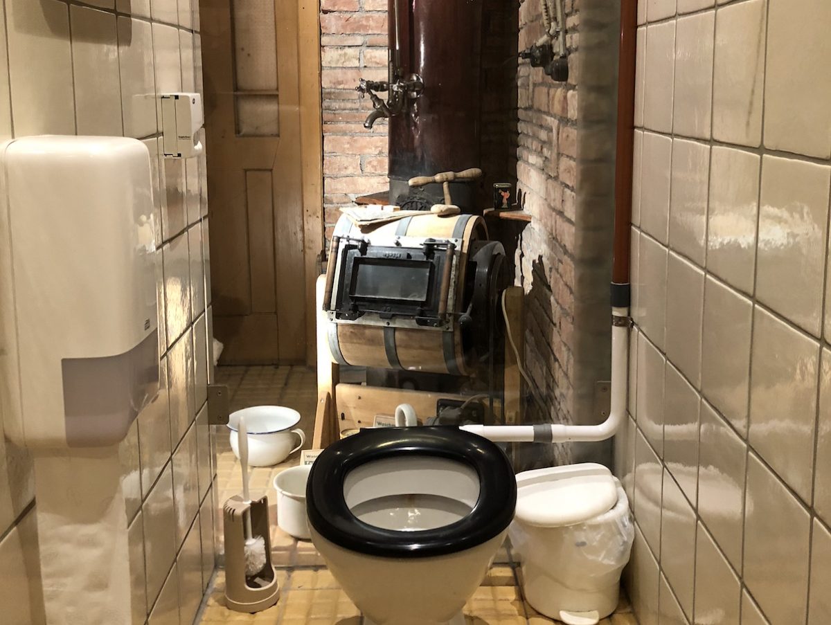 Toilette vor Glaswand zur Ausstellung.