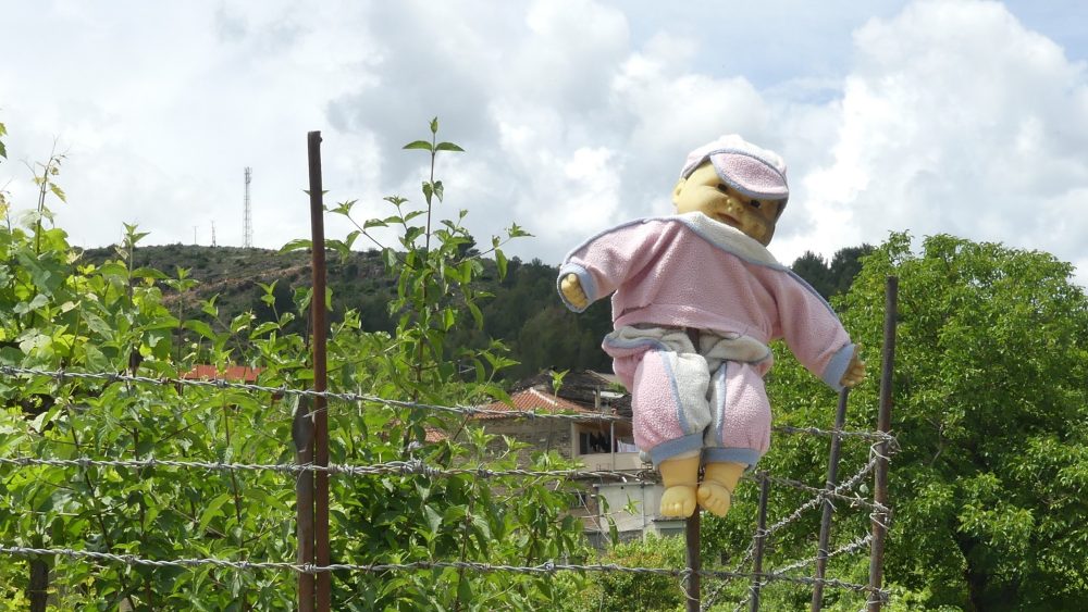 Eine Puppe hängt an einem Zaun.