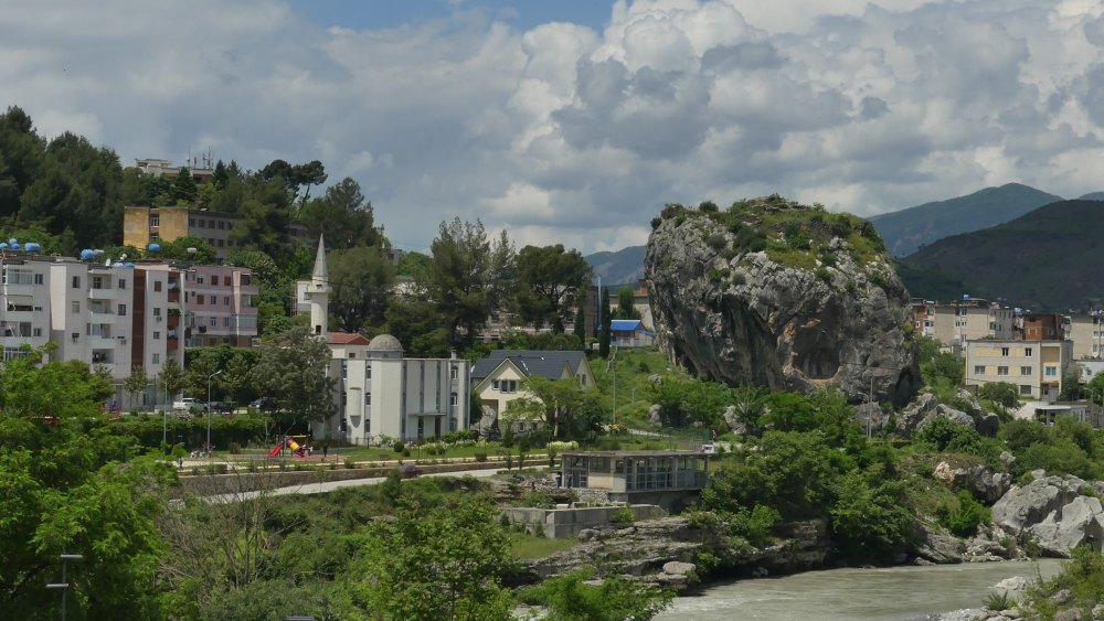 Stadtansicht von Permet mit Fluss und großem Felsen.