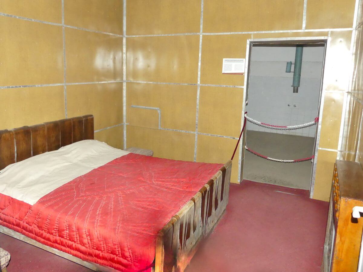 Schlafzimmer mit gelben Wänden und Doppelbett, eine weitere Tür führt ins Bad.