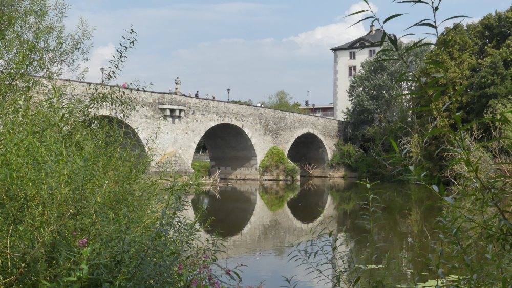 Brücke mit runden Bögen spiegelt sich in der Lahn.