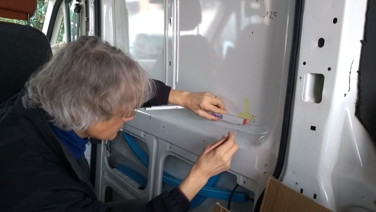 Marcus mit Zollstock und Stift beim Markieren des Ausschnitts für das Kastenwagen-Fenster.