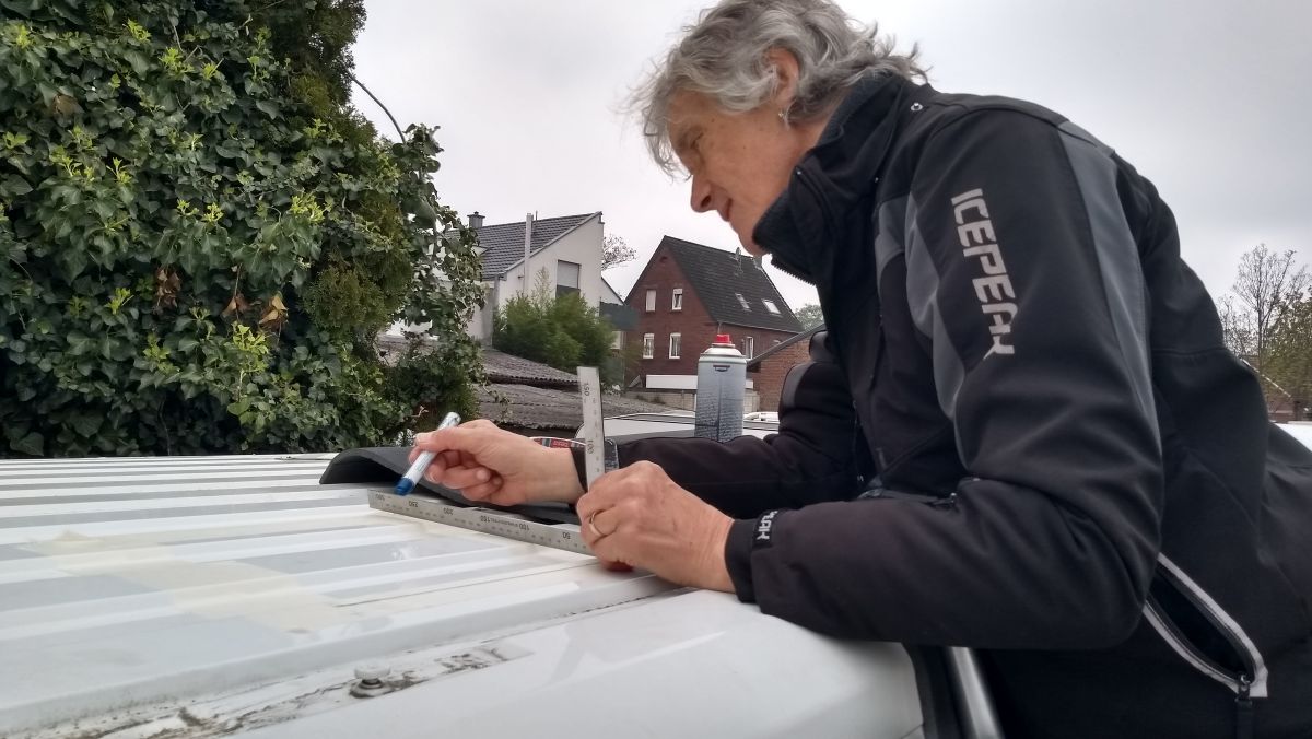 Marcus misst mit Zollstock und Bleistift das Dach aus.
