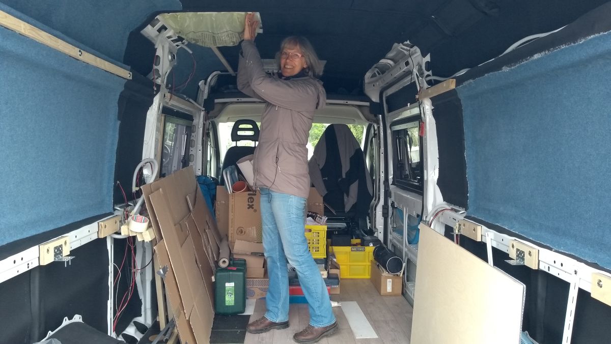 Gina klebt Plastikfolie unter die Decke im Kastenwagen.