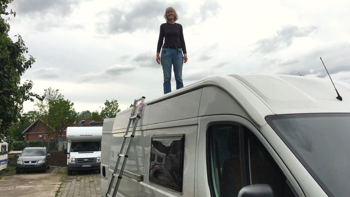Gina steht auf dem Dach des Campervans.
