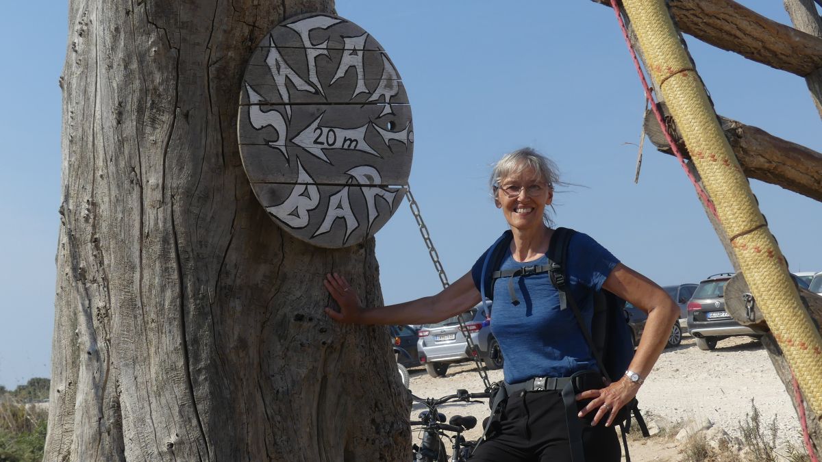 Gina steht neben einem Schild mit der Aufschrift 