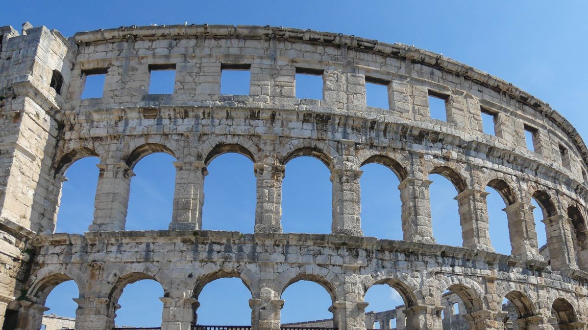 Fassade des Amphitheaters in Pula vor blauem Himmel.