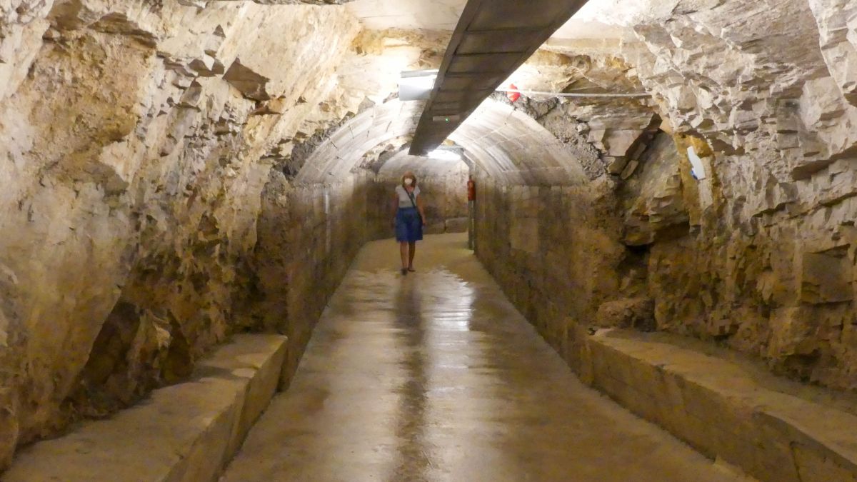 Gina läuft durch einen Tunnel mit gewölbter Decke.