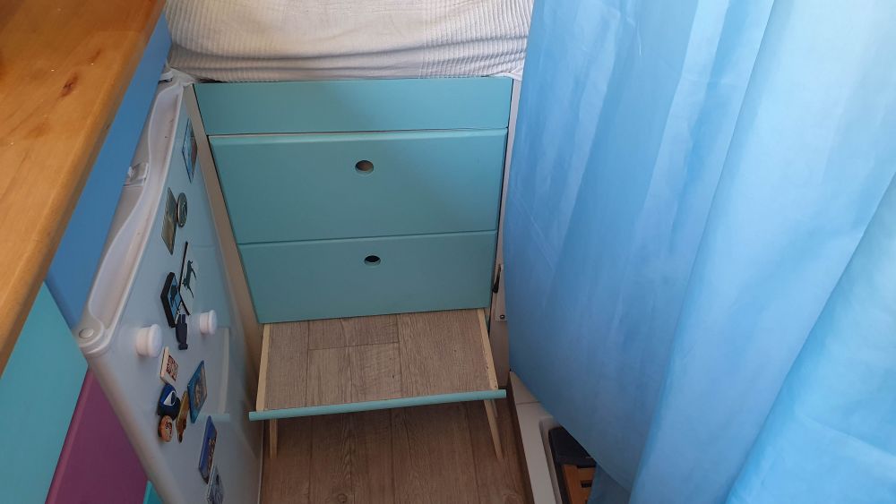 Hellblauer Schubladenschrank unter dem Bett, mit ausgezogener Trittstufe.