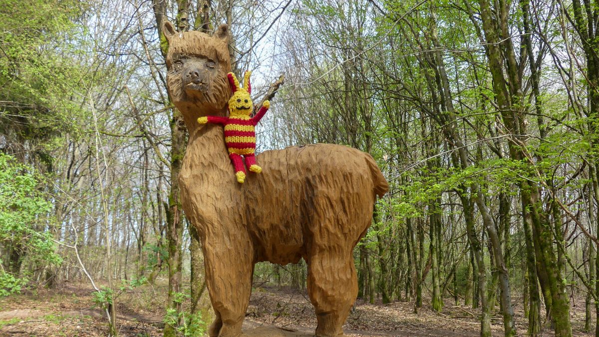 Reise-Ringel sitzt auf einer Holzskulptur eines Lamas.