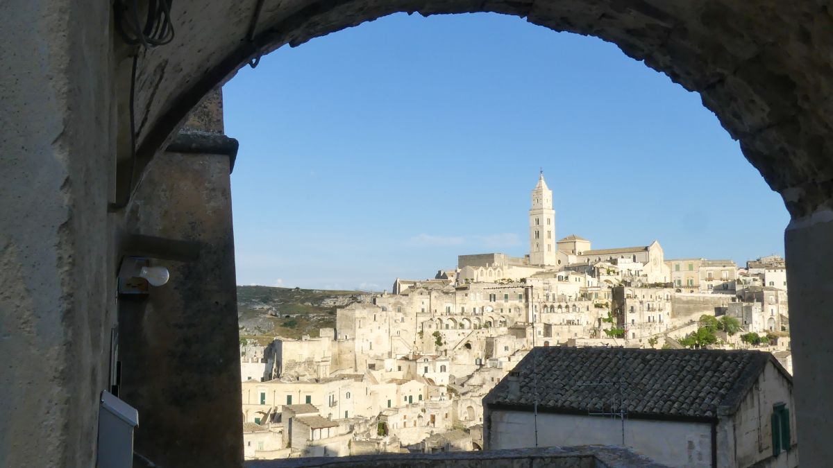 Blick durch einen Torbogen auf den Hügel der Stadt Matera.
