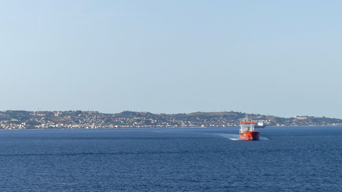 roter Frachter fährt auf der Meerenge von Messina.