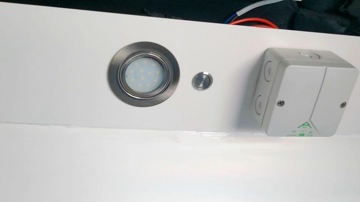 LED-Spot, Schalter und Verteilerkasten an der Rückwand der Dusche.