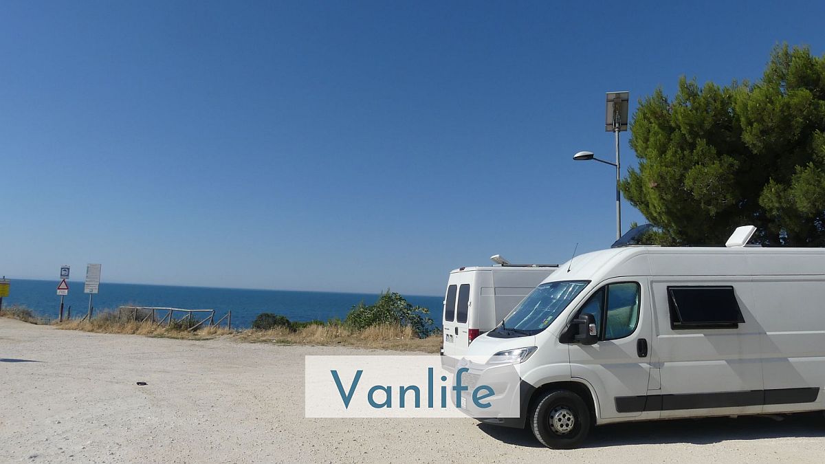 Zwei Vans stehen auf einem Parkplatz am Meer.