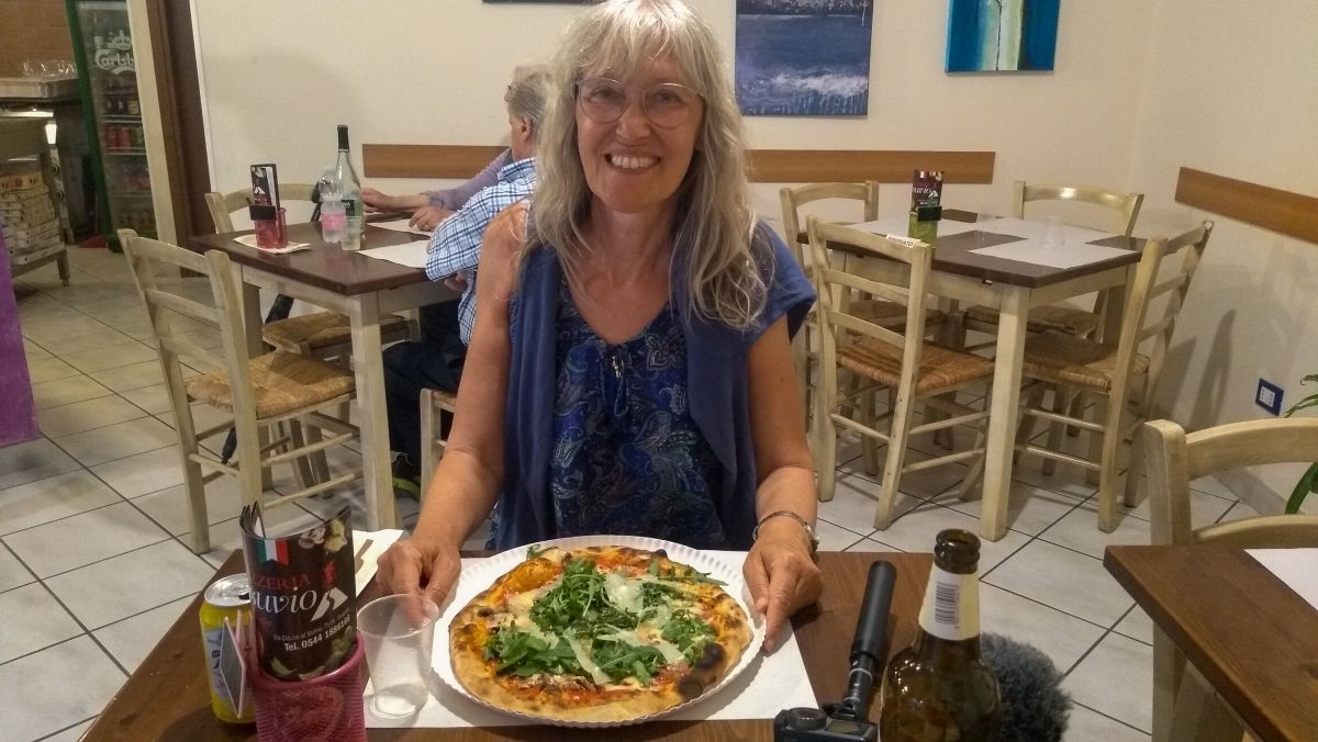 Gina sitzt vor einer großen Pizza.