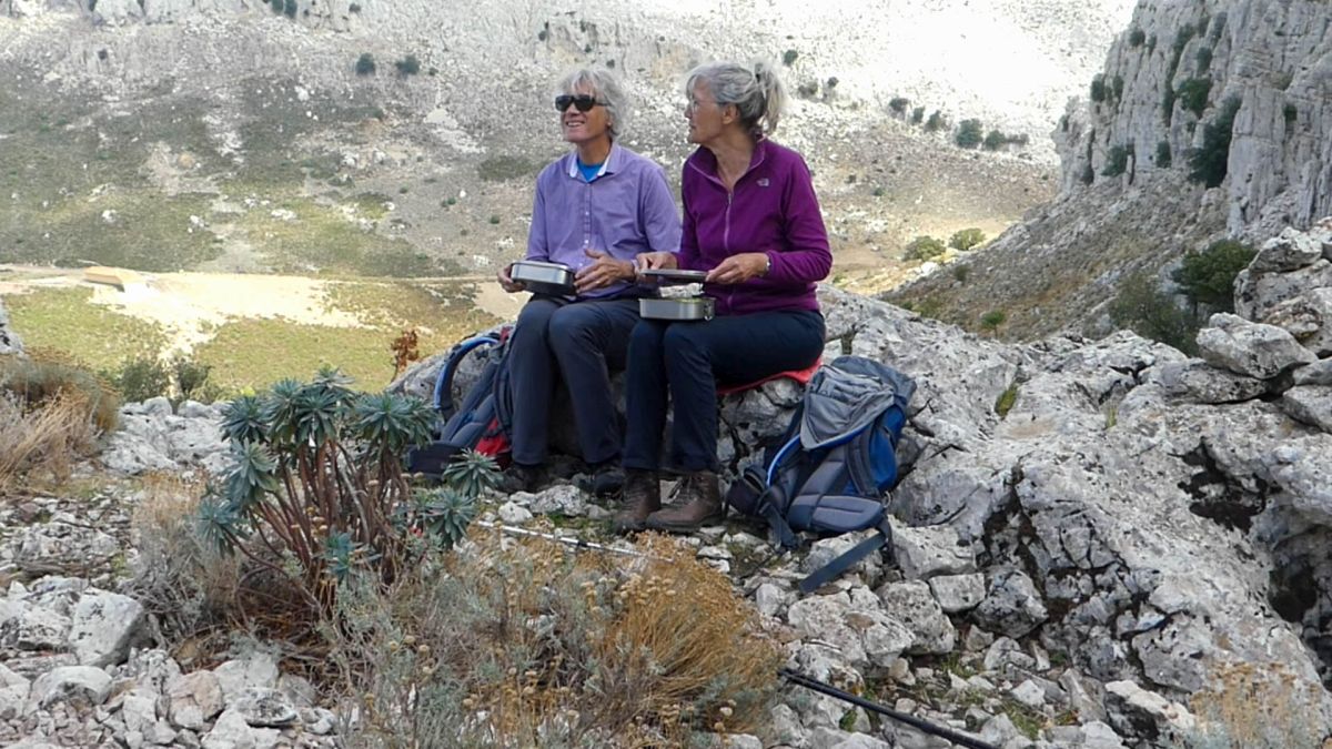 Gina und Marcus sitzen auf der Höhe des Bergkamms, dahinter Blick ins Tal.