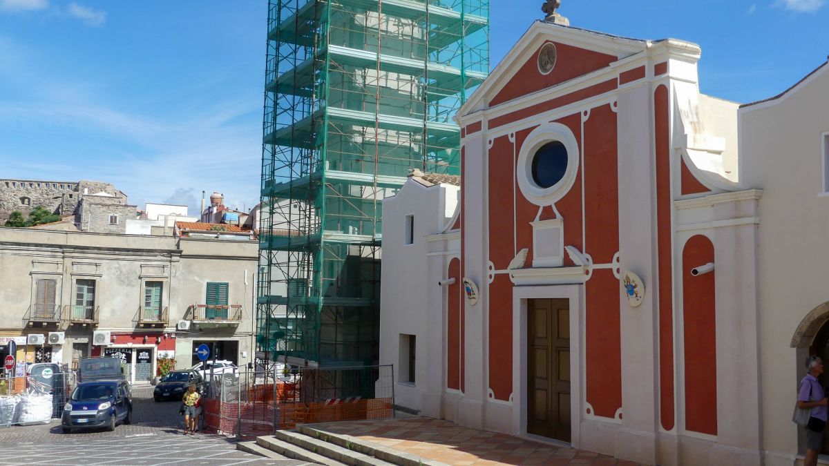 Kirche mit roter Fassade und eingerüstetem Turm.