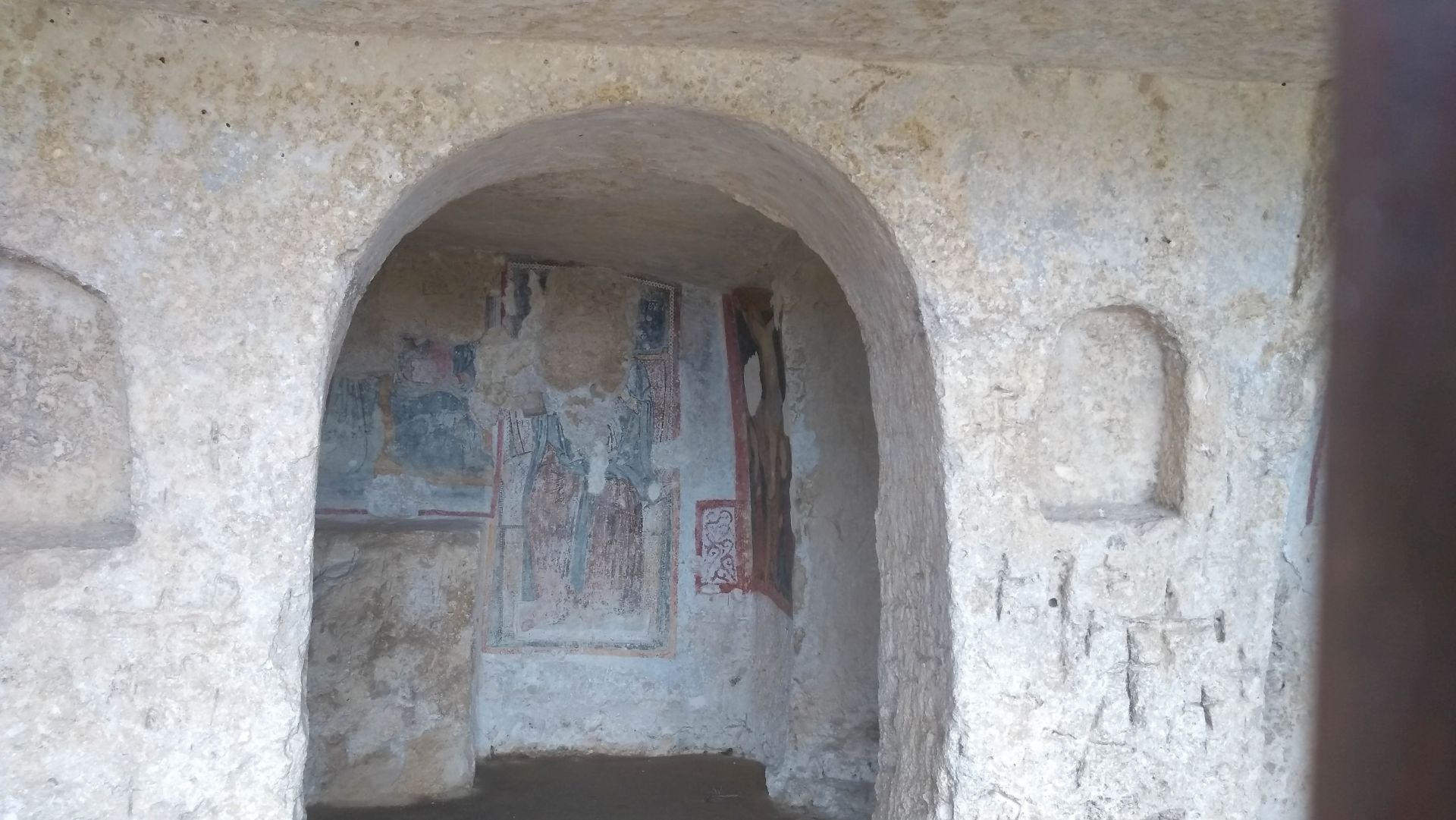 Bogen in der Felsenhöhle, dahinter Fresken an der Wand.