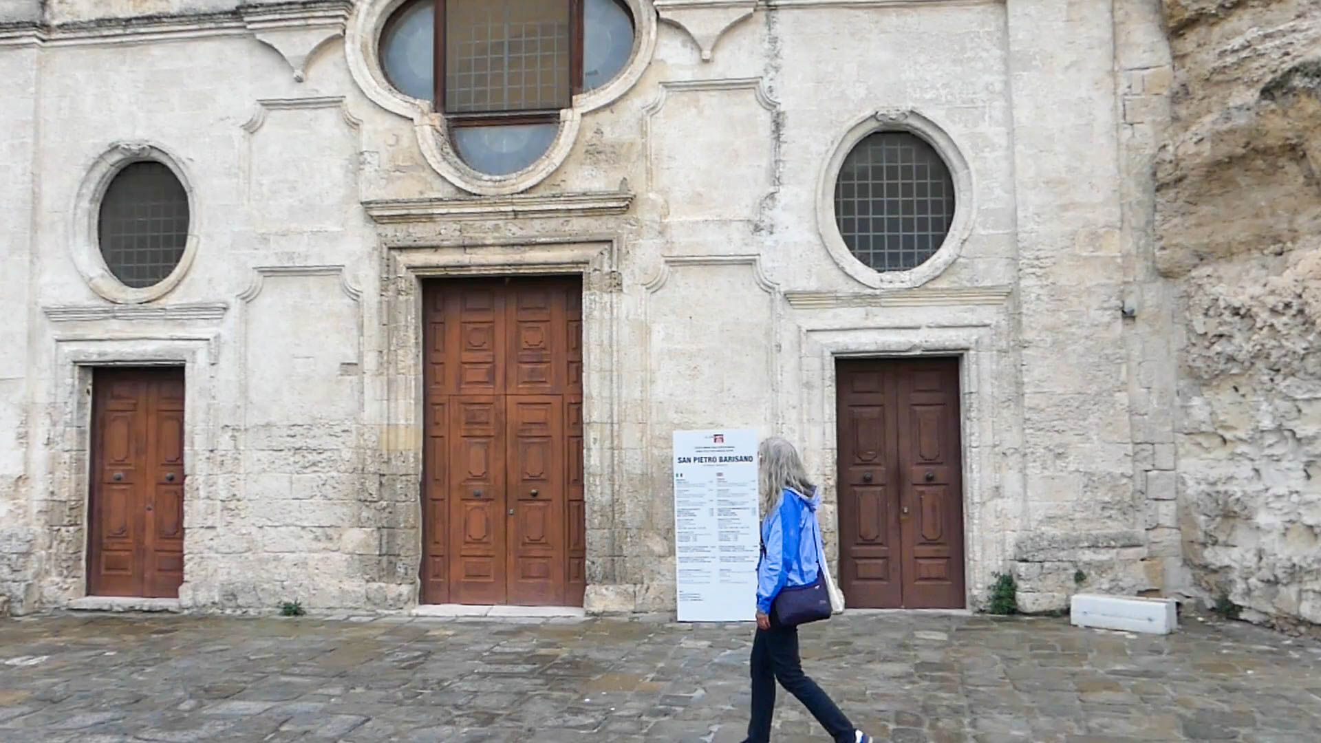 Gina läuft vor der Fassade der Kirche entlang.