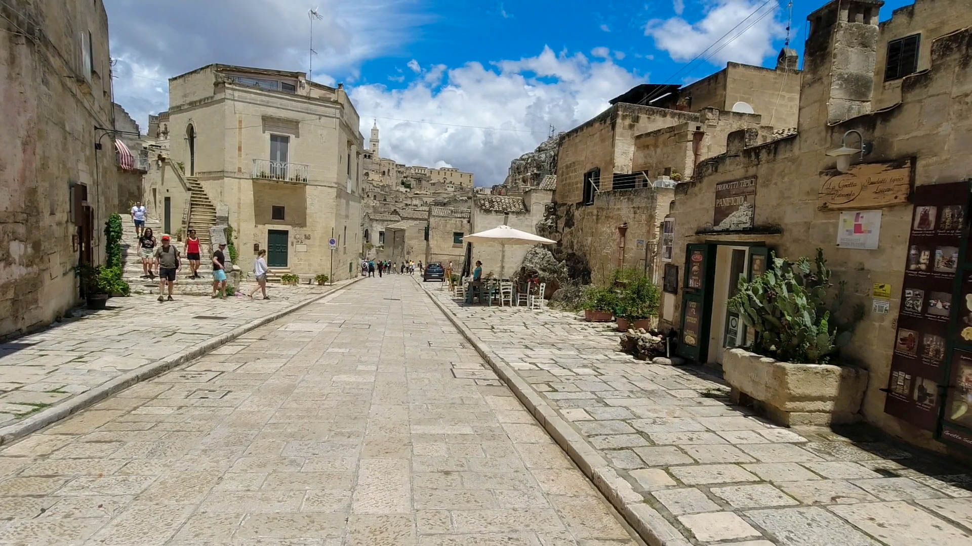Breite gepflasterte Straße mit Lokalen in den Sassi di Matera 